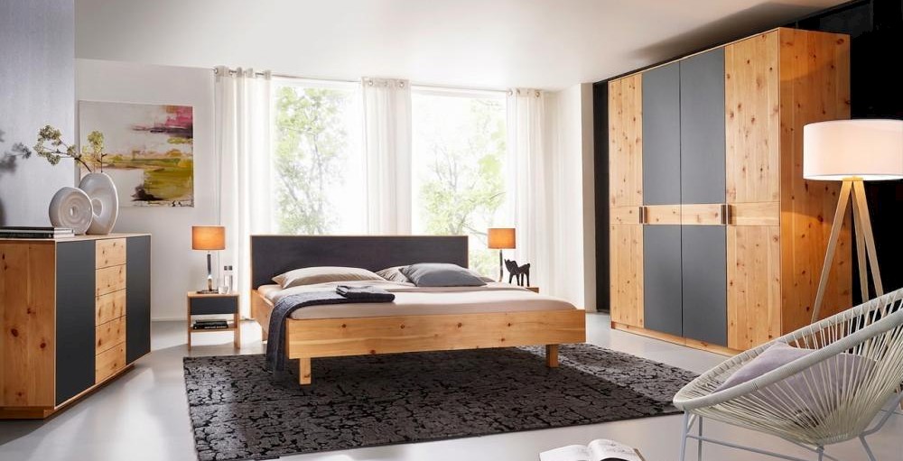 Holzschmiede Bett Jaso in Zirbe massiv mit gepolsterten Kopfteil und Kleiderschrank in Zirbe massiv mit Farbglas
