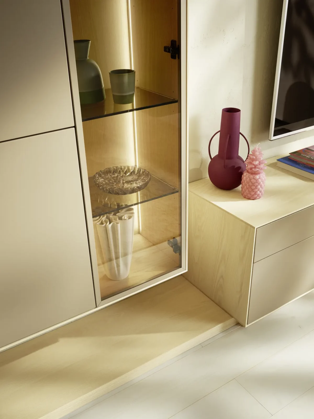 Anrei Puro Vitrine mit Glasfront, hellem Holz und integrierter Beleuchtung.