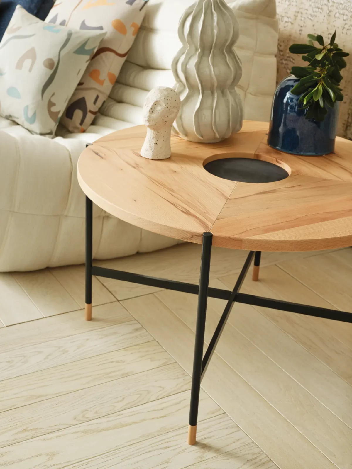Anrei Couchtisch mit runder Holzplatte und schwarzem Metallgestell.