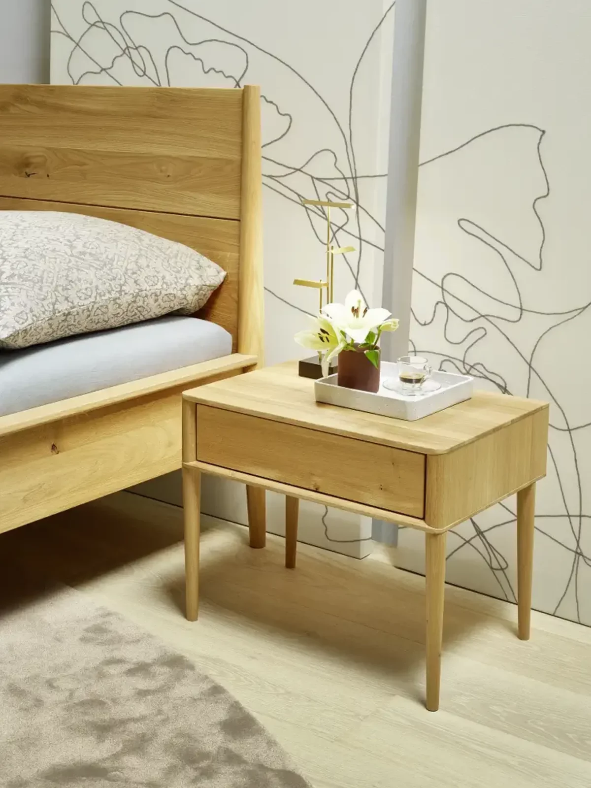 Anrei Juna Nachttisch aus hellem Holz mit schlanken Beinen und Schublade.