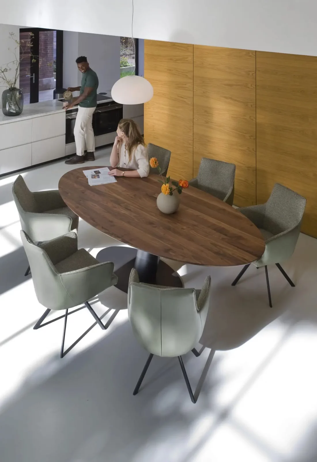 Esstisch Libra aus Holz mit ovaler Platte und schwarzem Mittelfuß.