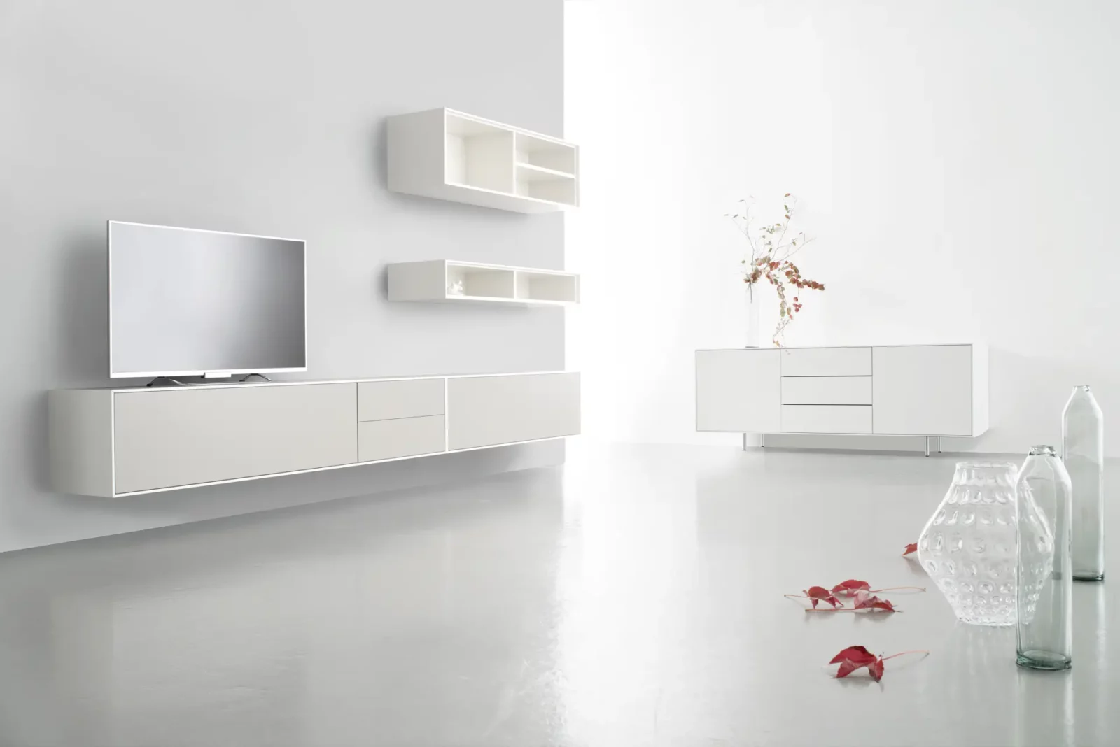 Hochwertige weiße Wohnwand mit schwebendem Sideboard und Hängeregalen.