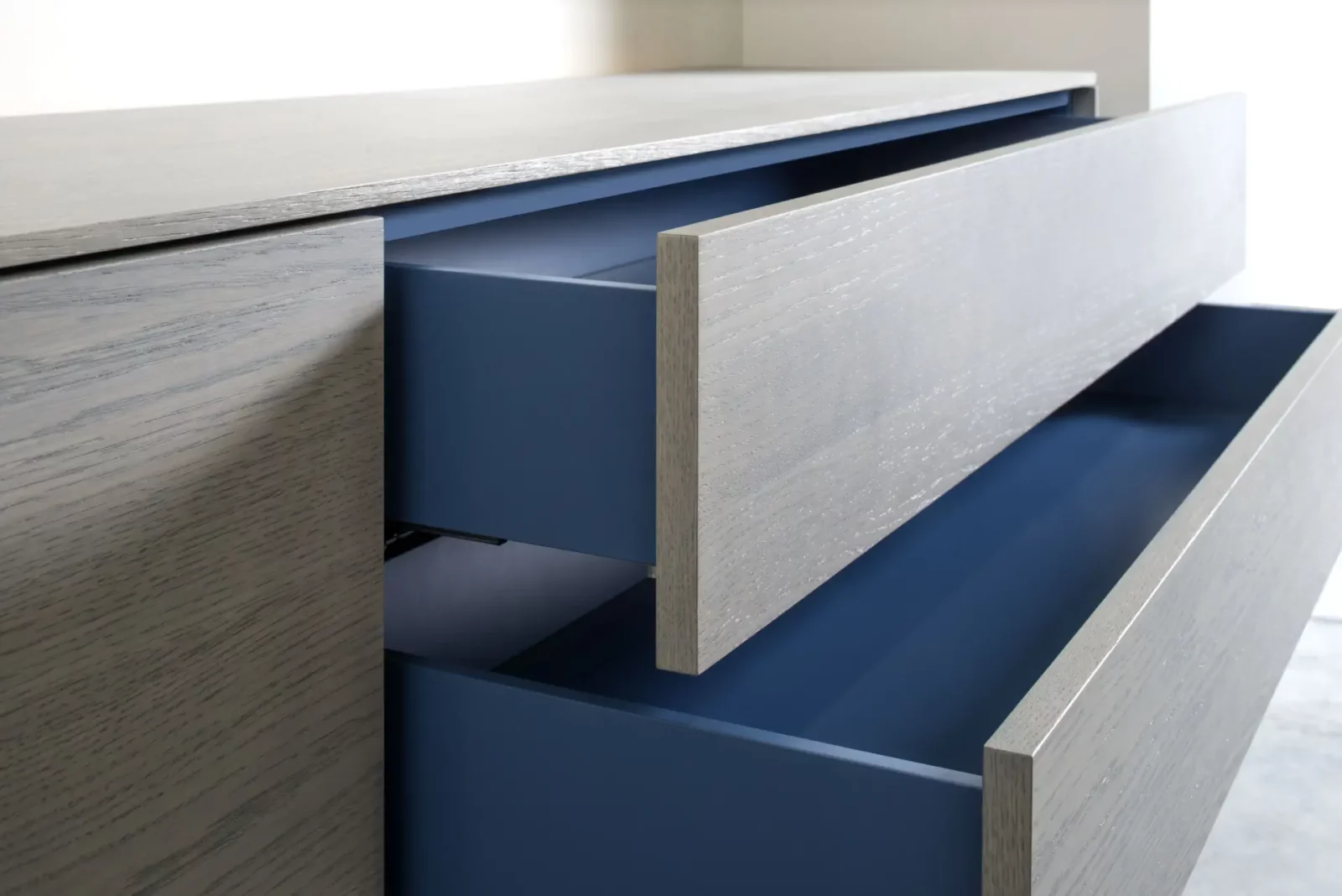 Kommode Gaya 022 mit grauer Holzoptik und blauen Schubladen.