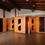 Eine exklusive Auswahl hochwertiger Infrarotkabinen aus edlem Holz in einem stilvoll beleuchteten Ausstellungsraum mit sichtbaren Holzbalken.