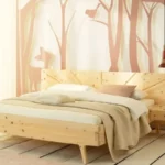 Ein elegantes Massivholzbett in einem Schlafzimmer mit einer Wandtapete, die einen stilisierten Wald mit einem Reh und Vögeln in sanften Tönen zeigt.