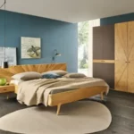 Ein luxuriöses Schlafzimmer mit einem Holzbett, das vor einer tiefblauen Wand steht, ergänzt durch einen modernen Kleiderschrank und Kunstwerke.