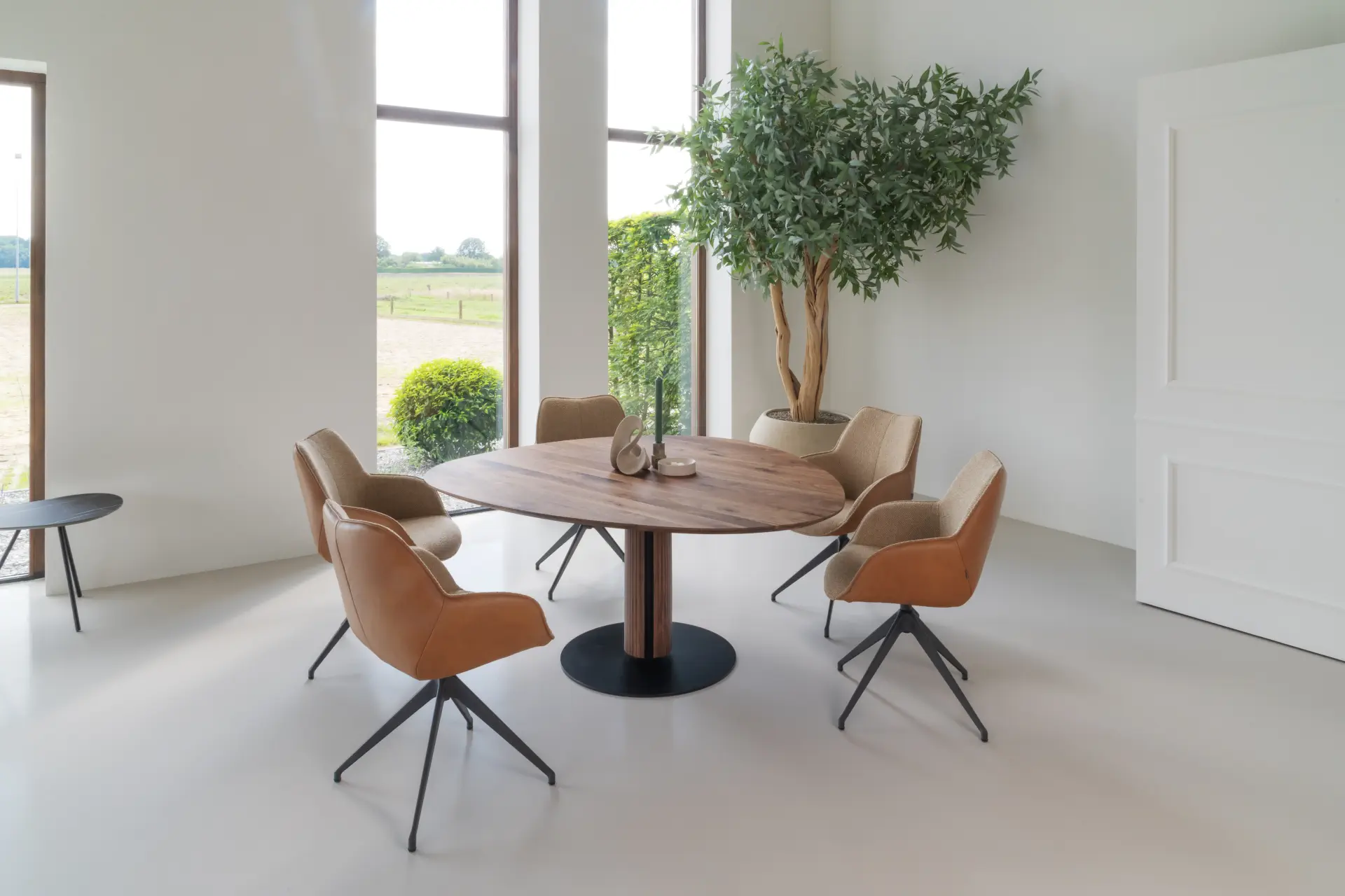 Runder Holztisch mit fünf modernen, gepolsterten Esszimmerstühlen in Beige und Braun.