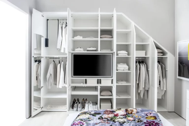Weißer Einbauschrank mit TV, offenen Regalen und Kleiderstangen.