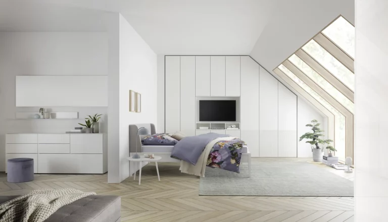 Schlafzimmer mit weißem Einbauschrank und grauem Polsterbett, Modell Maria.