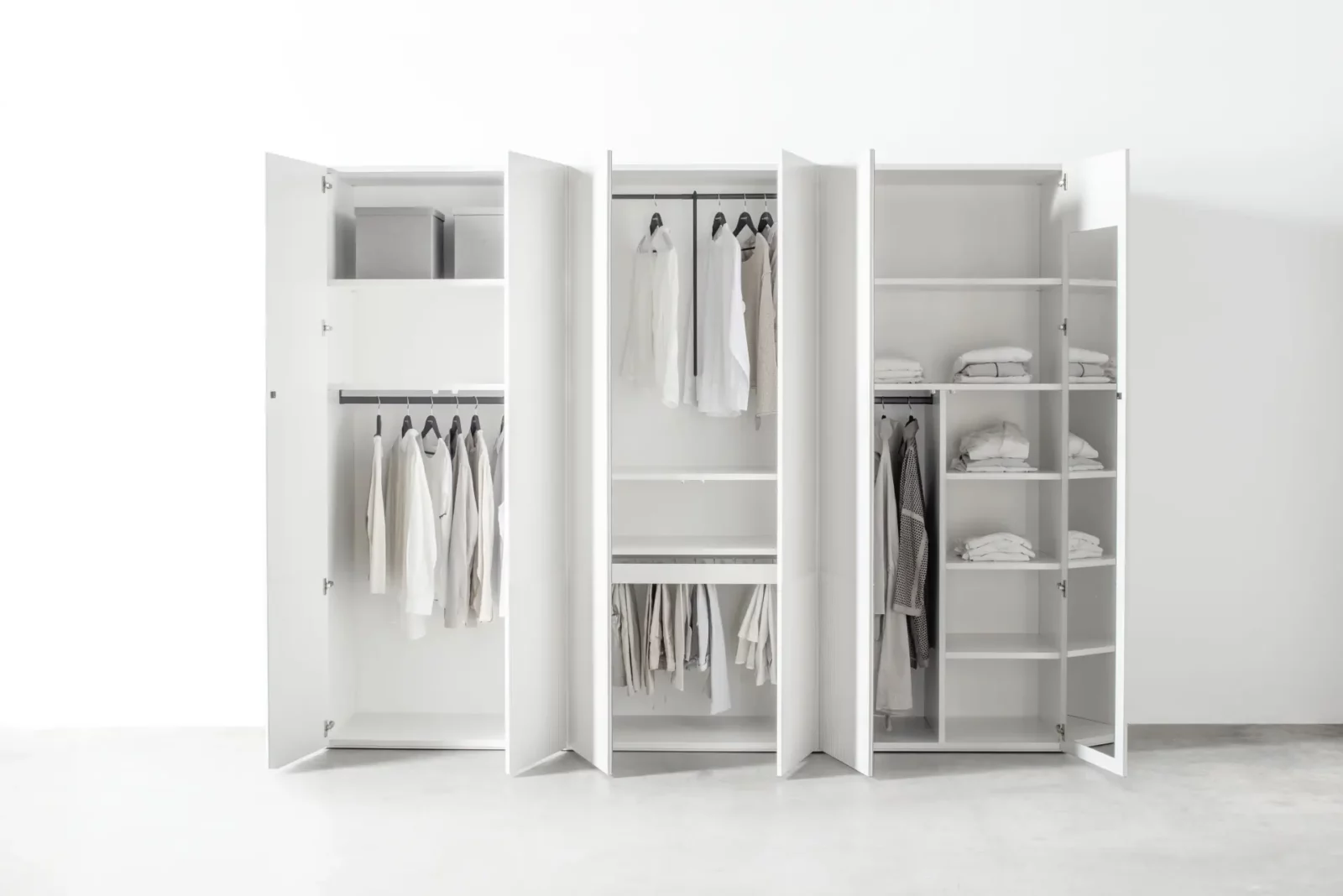 Weißer Kleiderschrank aus Holz mit offenen Türen und vielseitiger Innenaufteilung.
