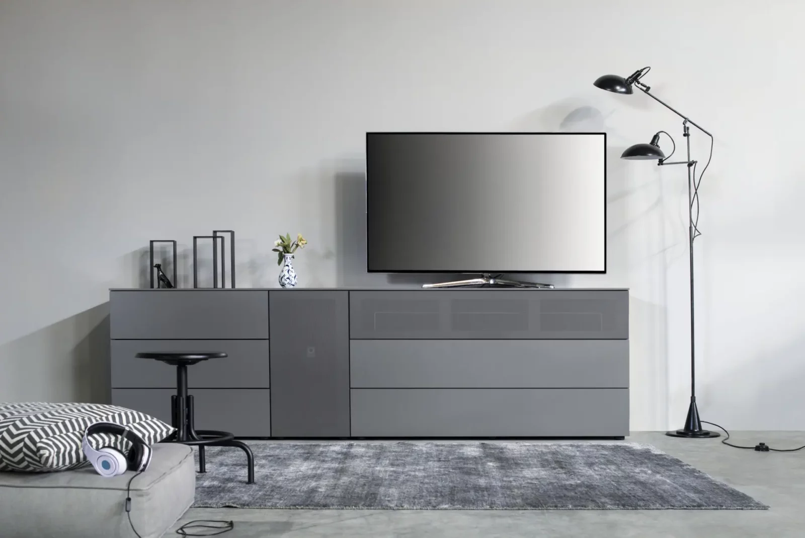 Graues Sideboard Nubo 007 mit Schubladen und integriertem TV-Gerät.