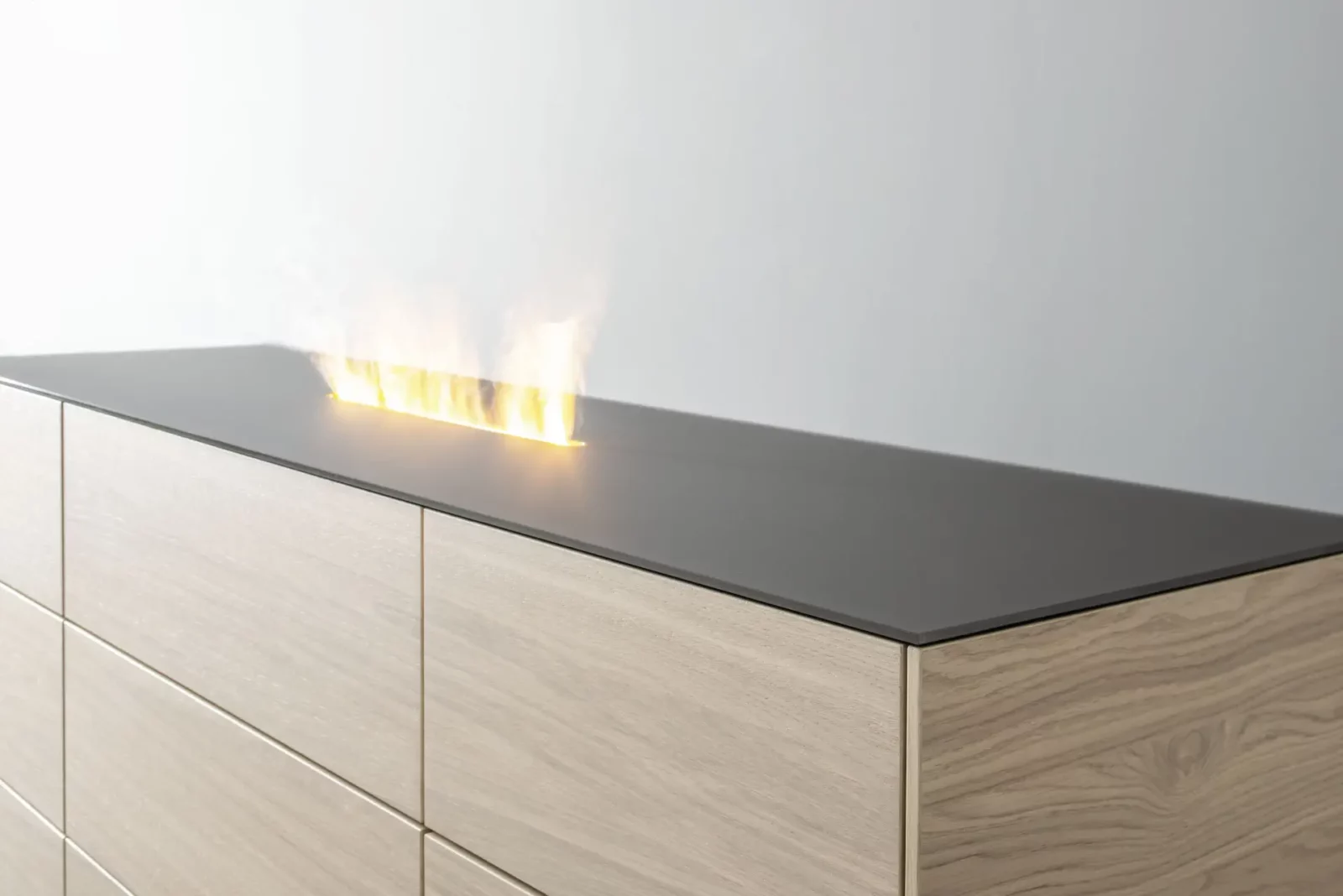 Nubo 068 Kommode aus hellem Holz mit schwarzer Oberfläche und Flammenoptik.