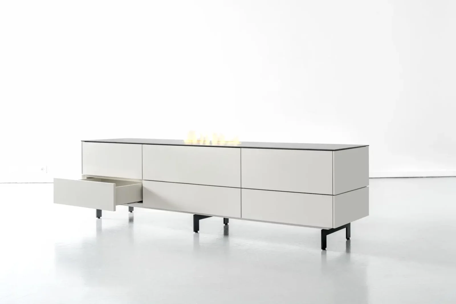 Sideboard Nubo 094, weiß, mit schwarzen Beinen und offener Schublade.