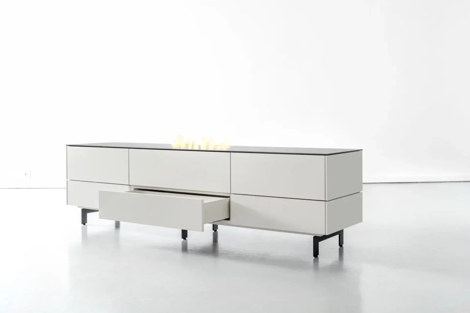 Sideboard Nubo 097 in Weiß mit schwarzer Platte und offenen Schubladen.