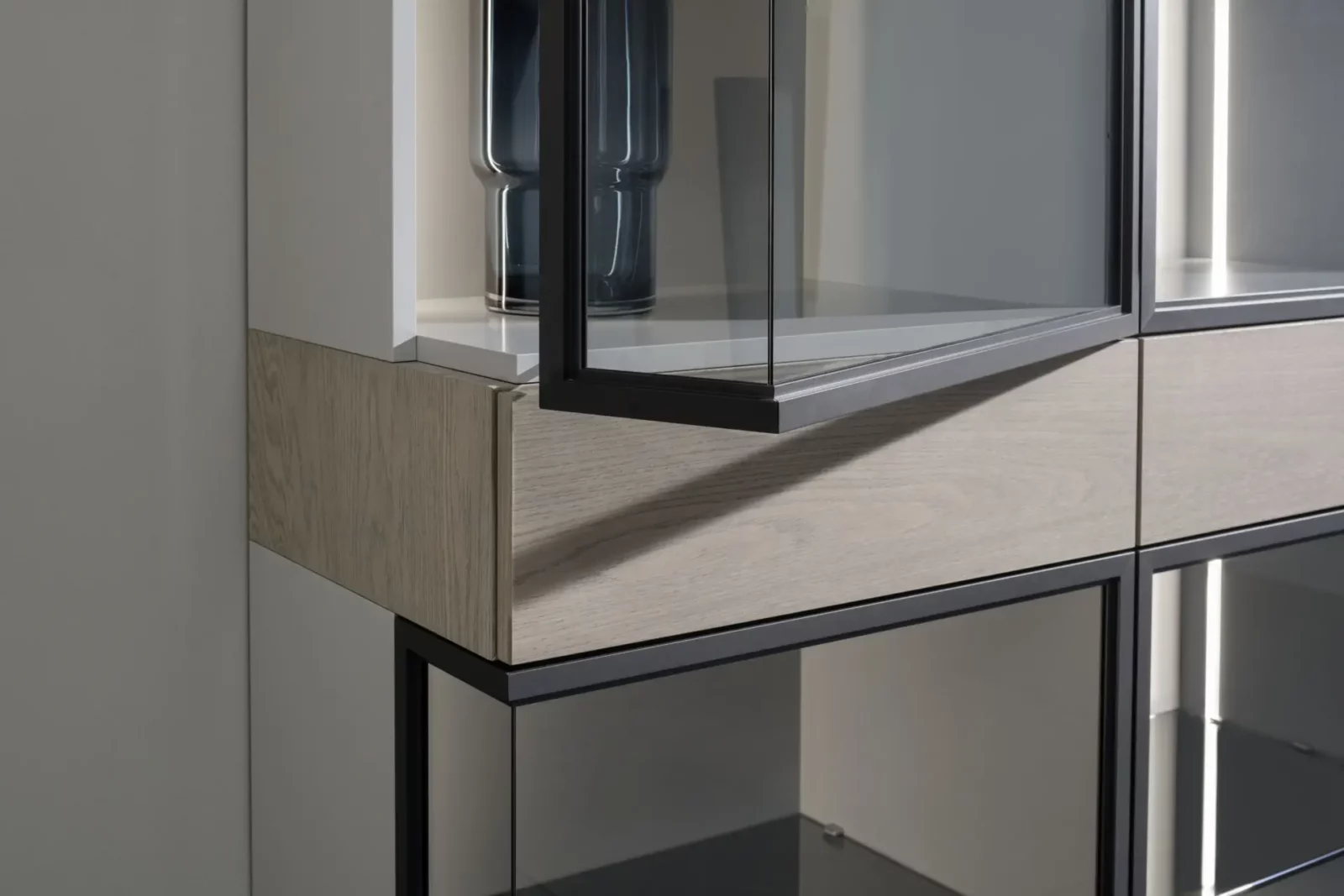 Vitrine Nubo 117 mit Glasfronten, Holzdetails und schwarzem Metallrahmen.
