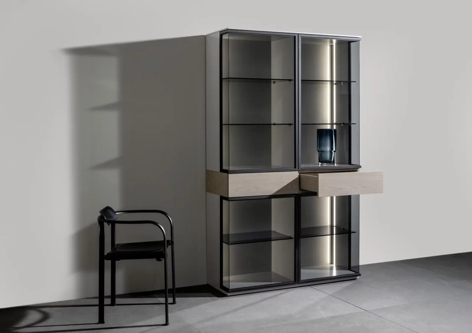 Vitrine Nubo 120 mit Glasfronten, Holzschubladen und schwarzem Metallrahmen.