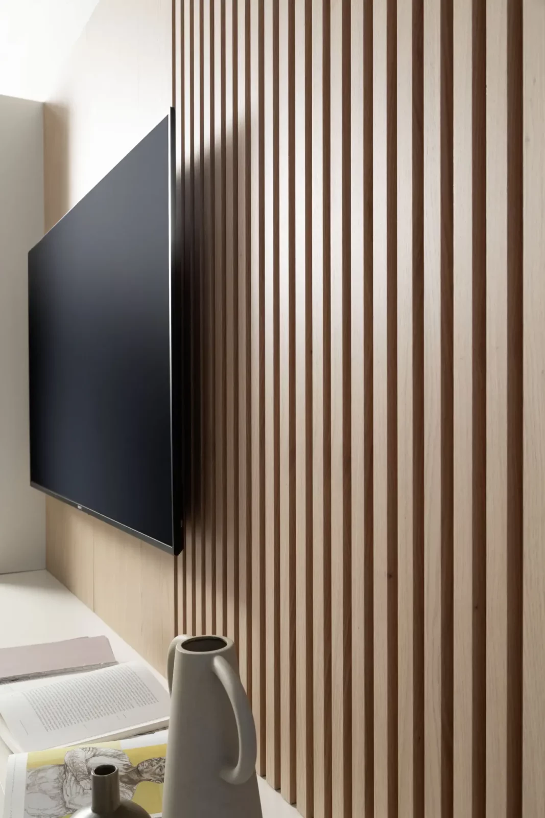 Nubo 150 Wandverkleidung aus hellem Holz mit vertikalen Lamellen.