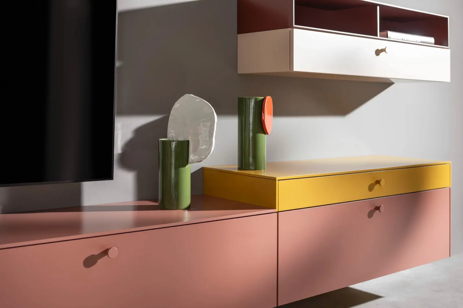 Sideboard Nubo 195 in Rosa und Gelb mit grünen Vasen.