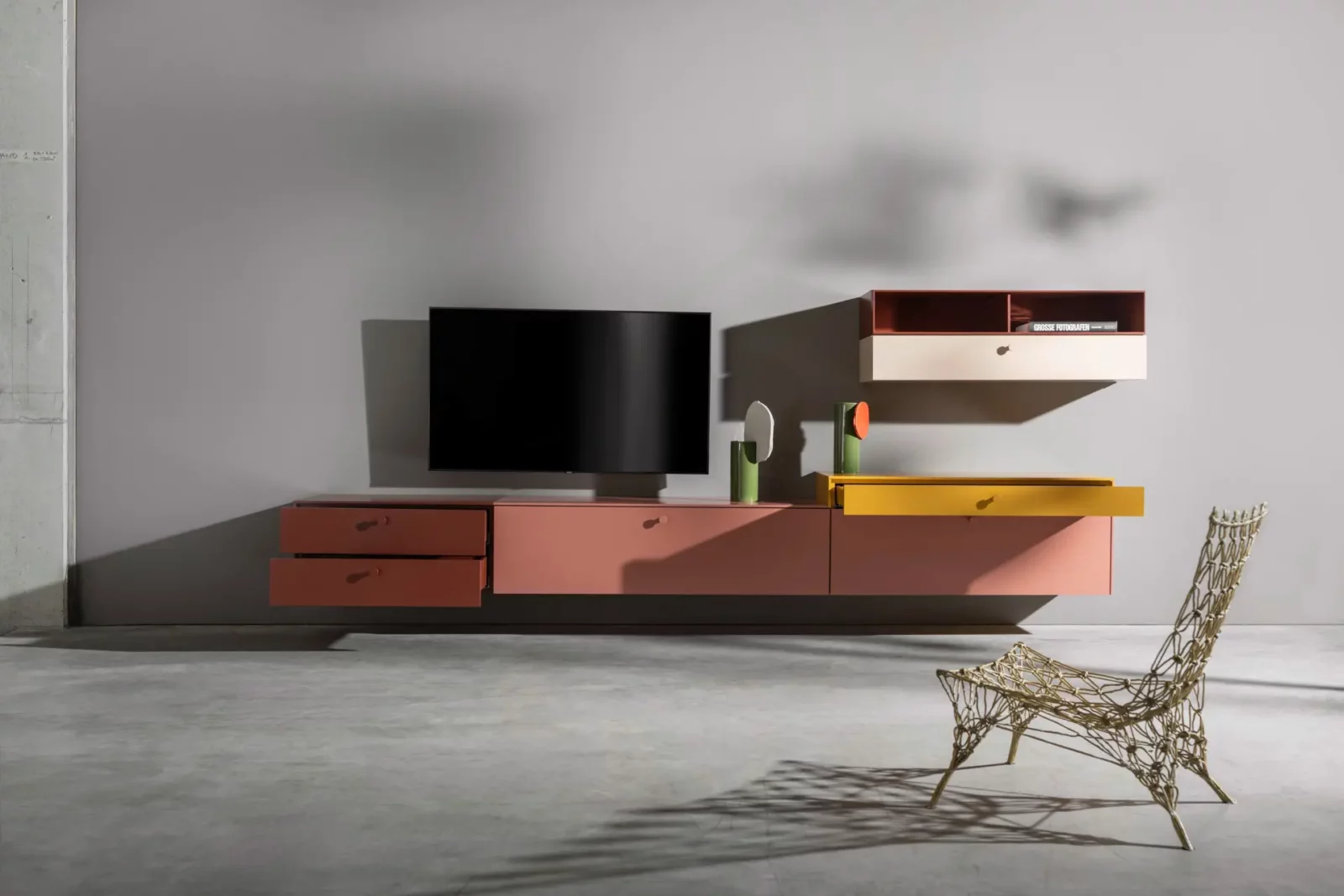 Nubo 198 Hängeschrank in Rosa und Gelb mit offenen Fächern.