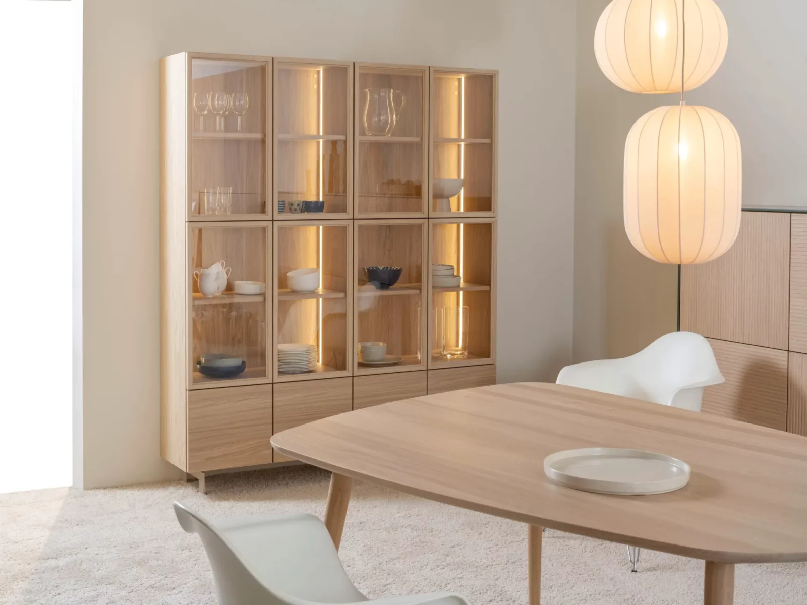Vitrine aus hellem Holz mit Glastüren und integrierter Beleuchtung.