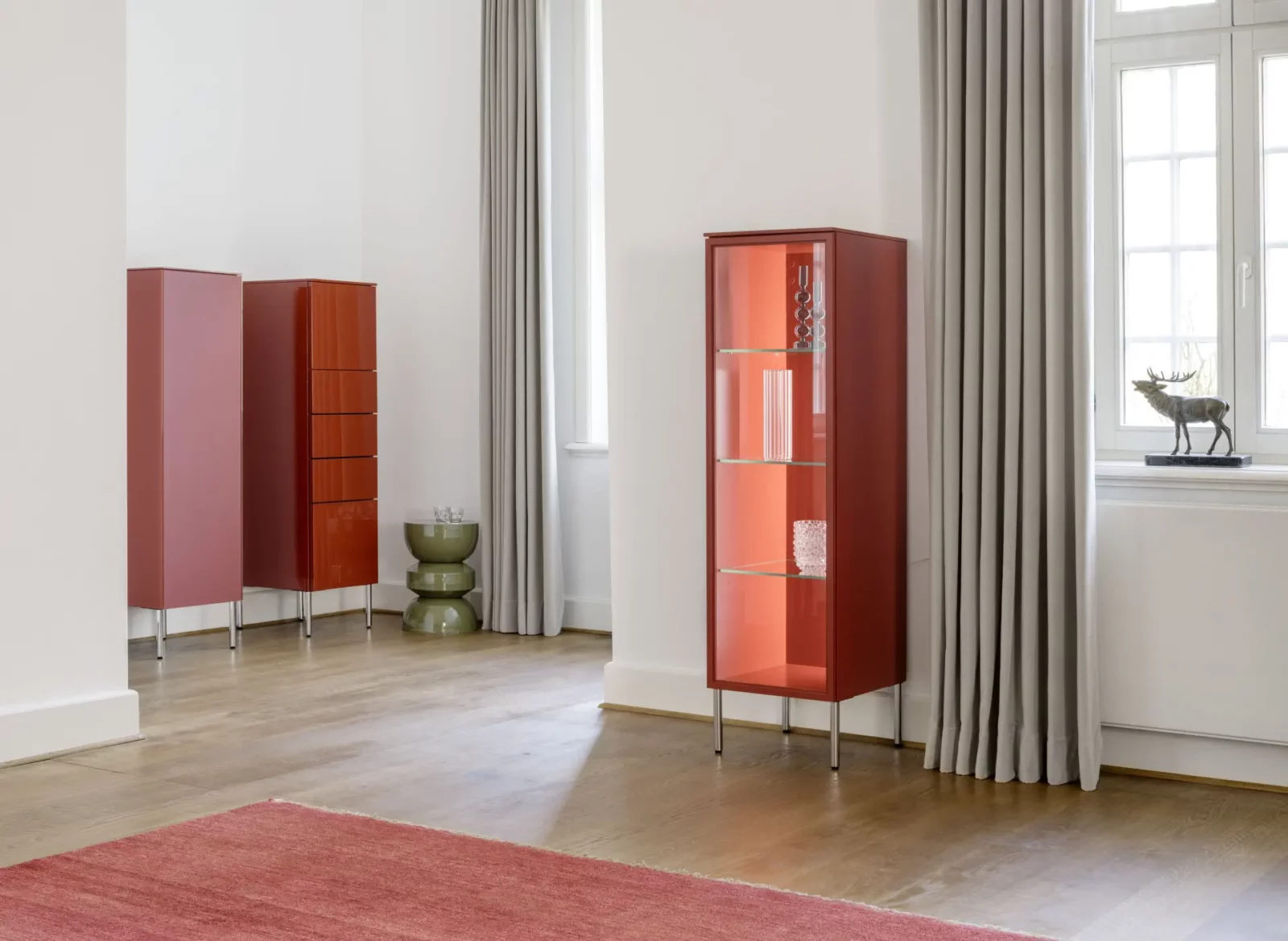 Vitrine Nubo 263 in Rot mit Glasböden und Metallfüßen.