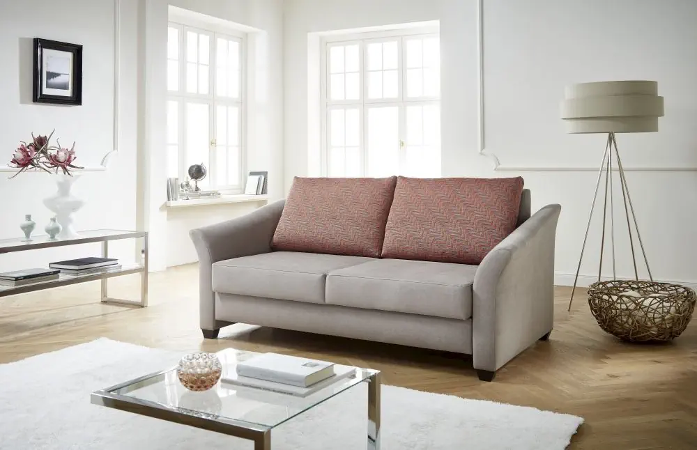 Schlafsofa Flexi mit grauem Korpus und gemusterten roten Rückenkissen.