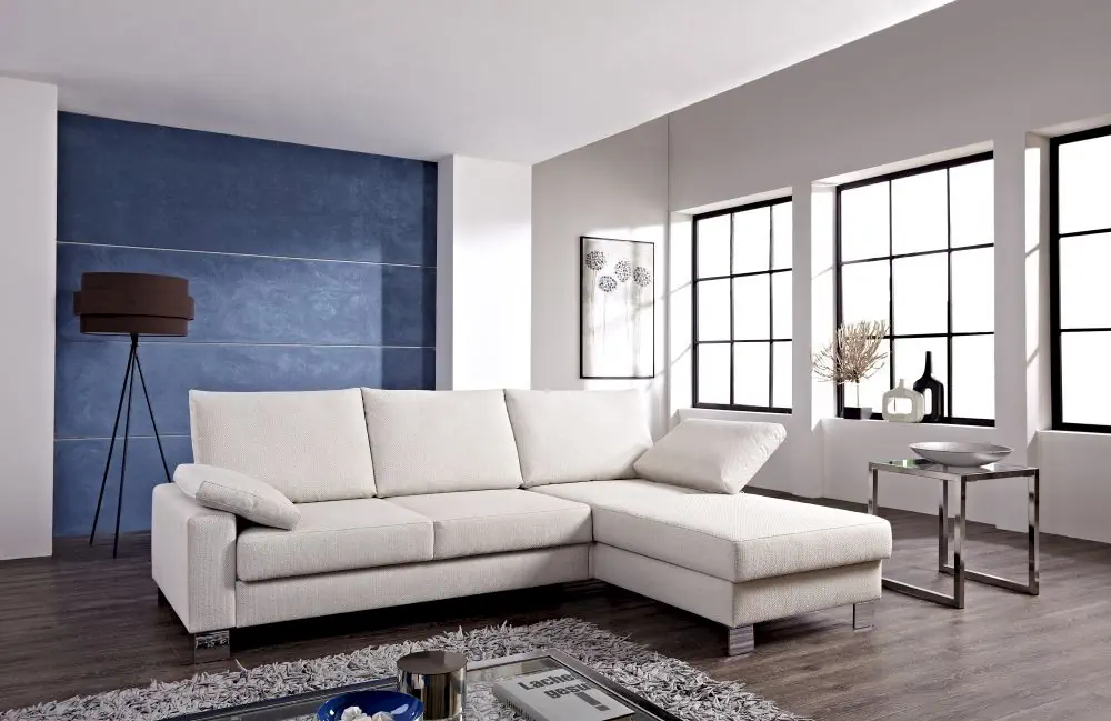 Schlafsofa Flexi in cremefarbenem Stoff mit L-Form und Metallfüßen.