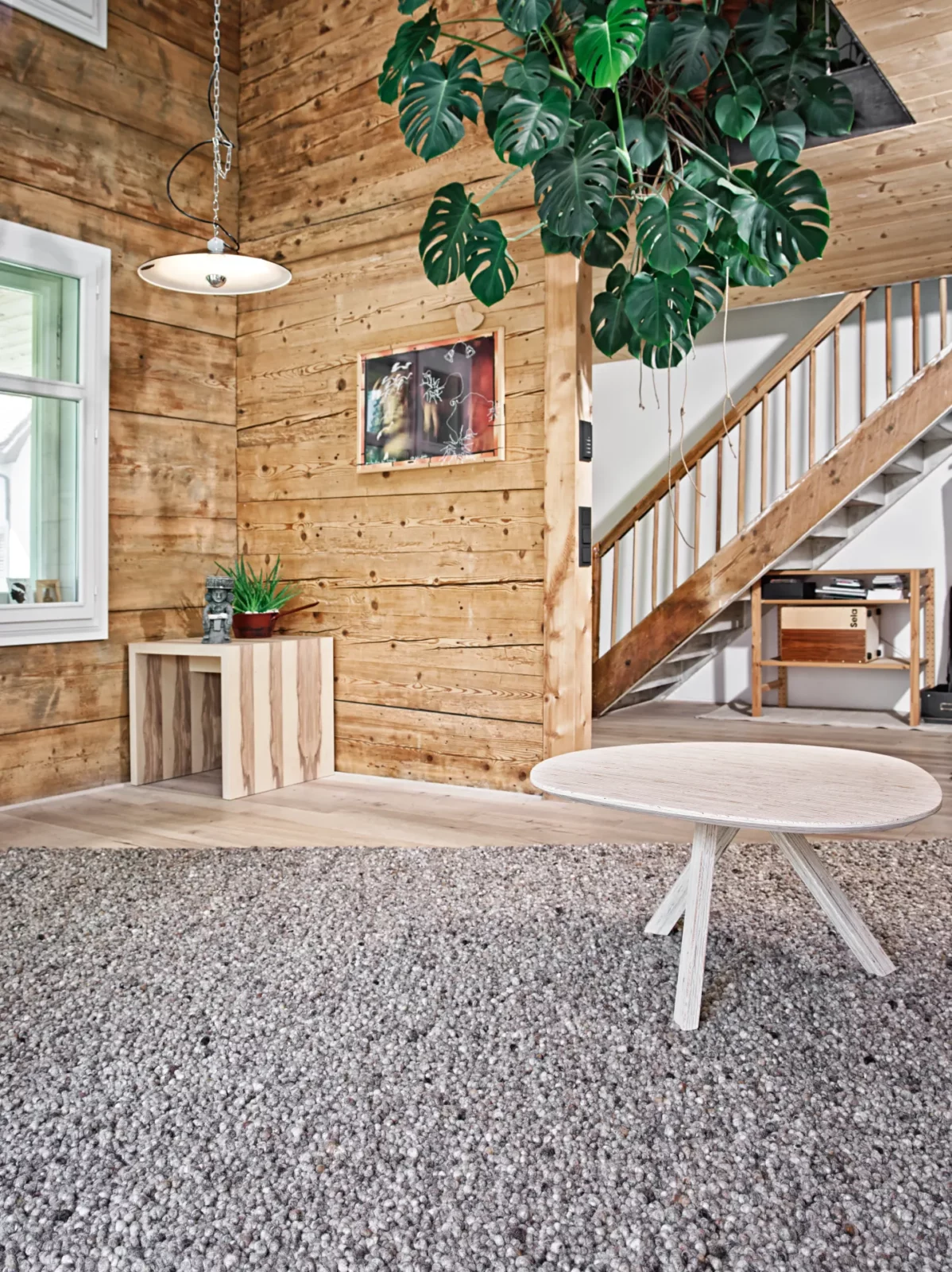 Runder Holztisch mit heller Holzmaserung auf grauem Teppich.