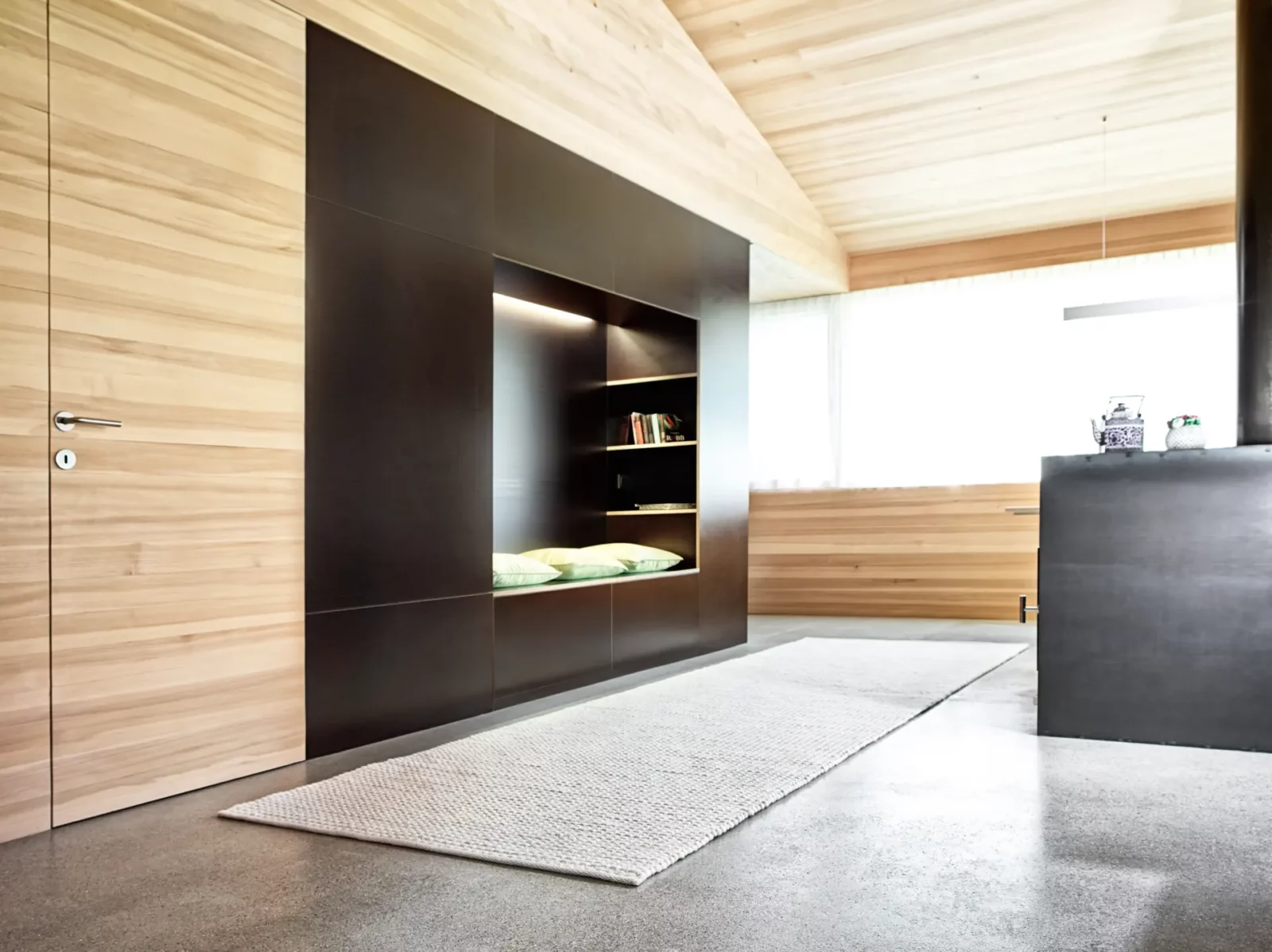 Einbauschrank aus dunklem Holz mit integrierter Sitznische und Regalen.