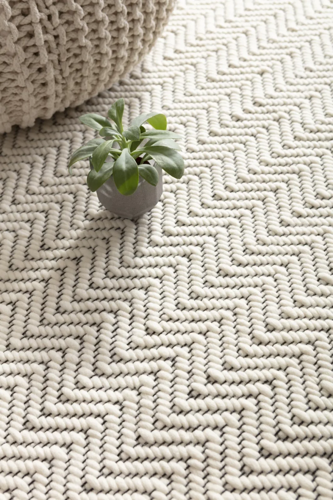 Tisca Zig Zag Teppich in cremeweißem Zickzack-Muster mit Pflanze.