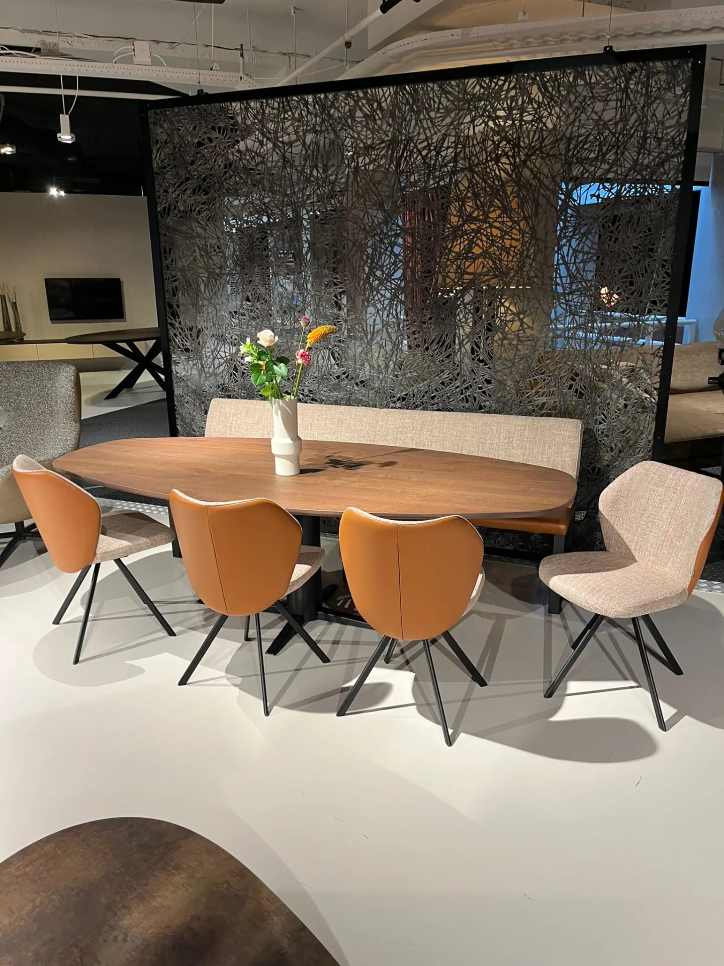 Esstisch-Set mit Holzplatte, beigen Polsterbänken und orangefarbenen Stühlen.