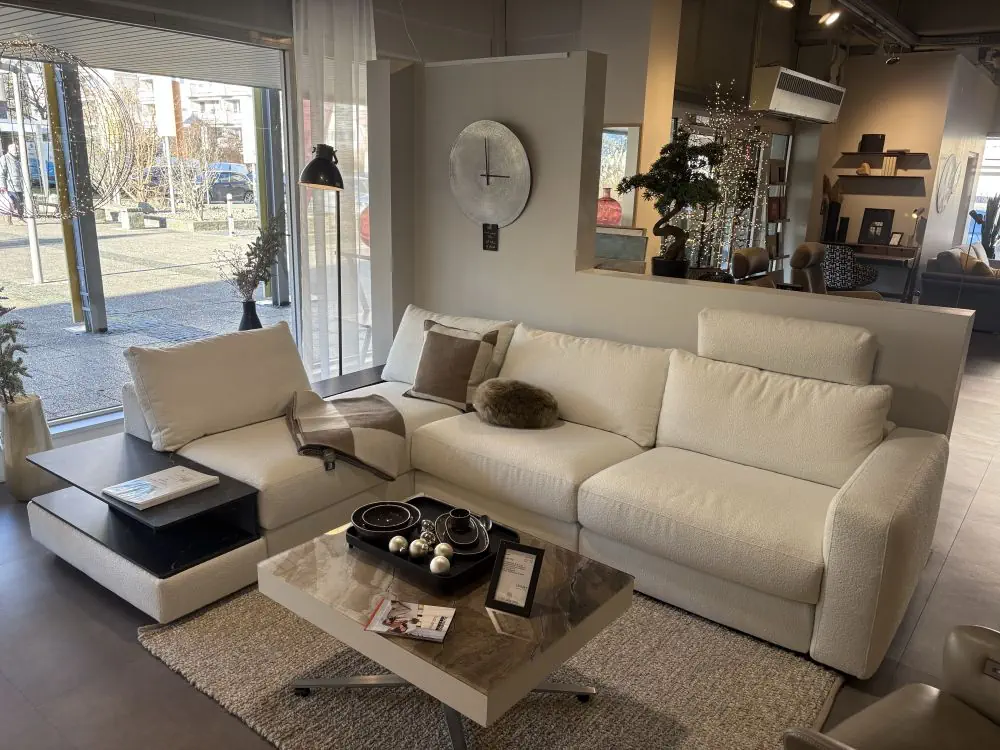 Ecksofa Gina in cremefarbenem Stoff mit integriertem Beistelltisch.