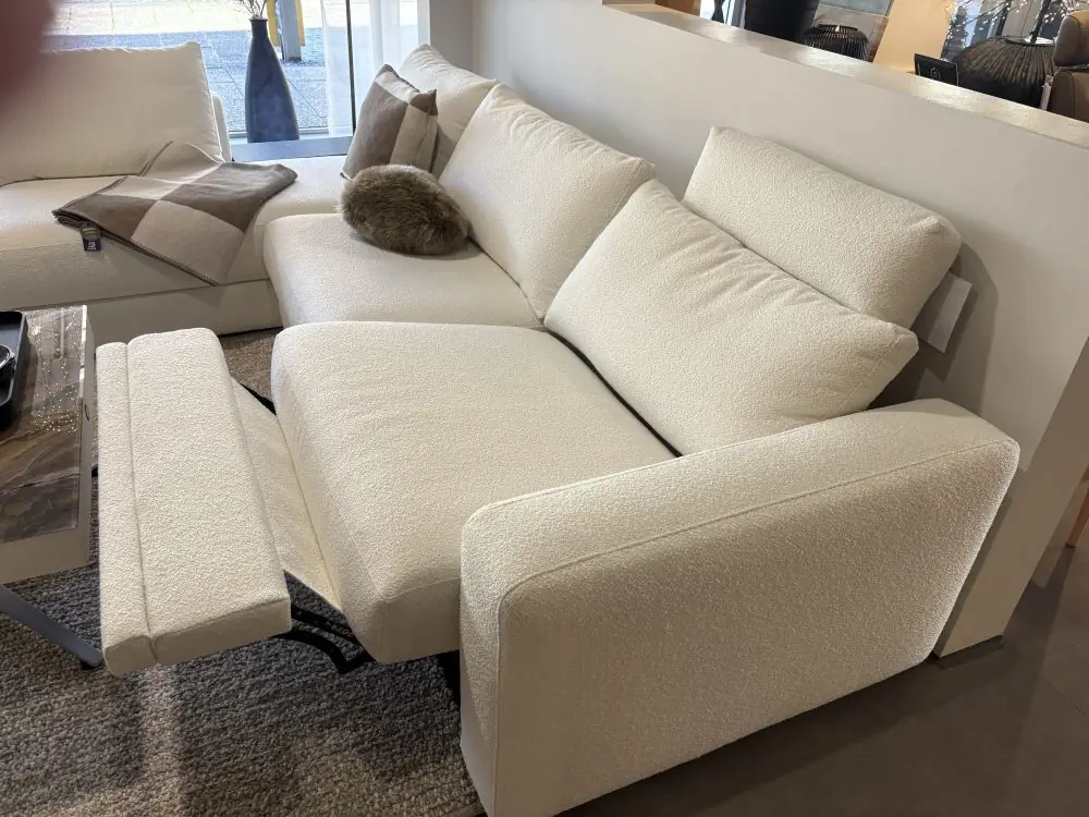 Ecksofa Gina in cremefarbenem Stoff mit verstellbarer Fußstütze.