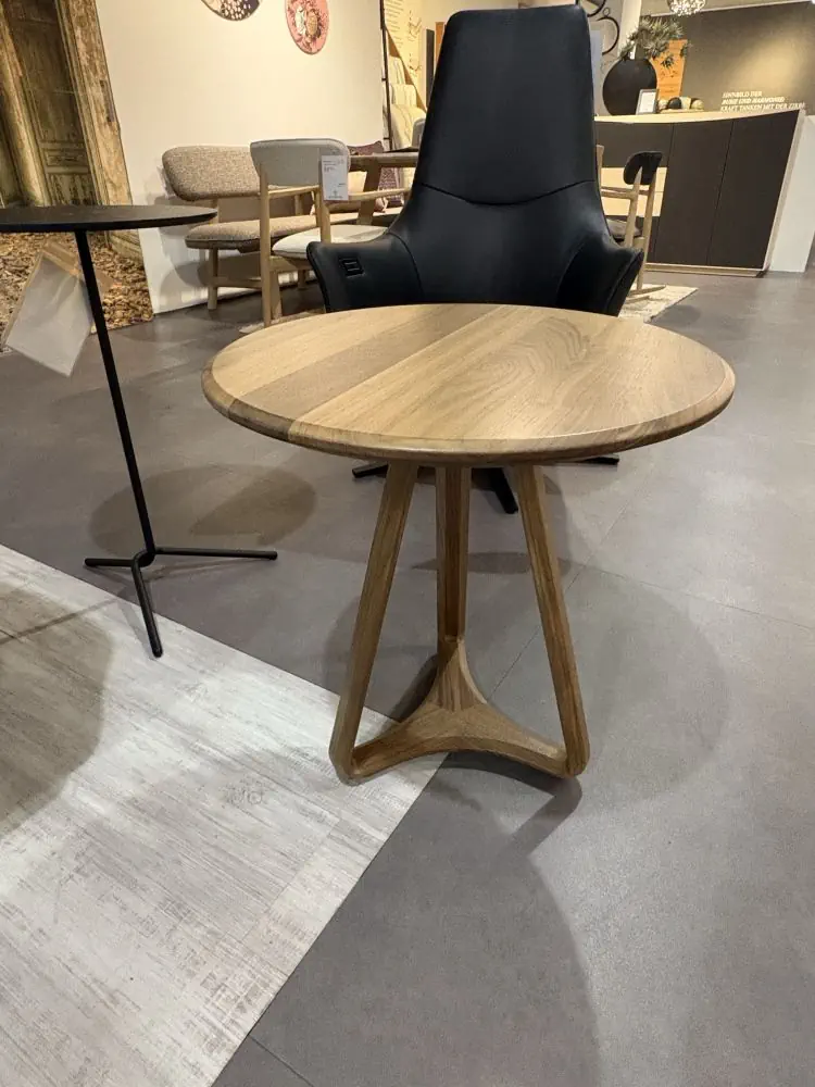 Runder Holztisch mit dreibeinigem Gestell in natürlicher Holzoptik.
