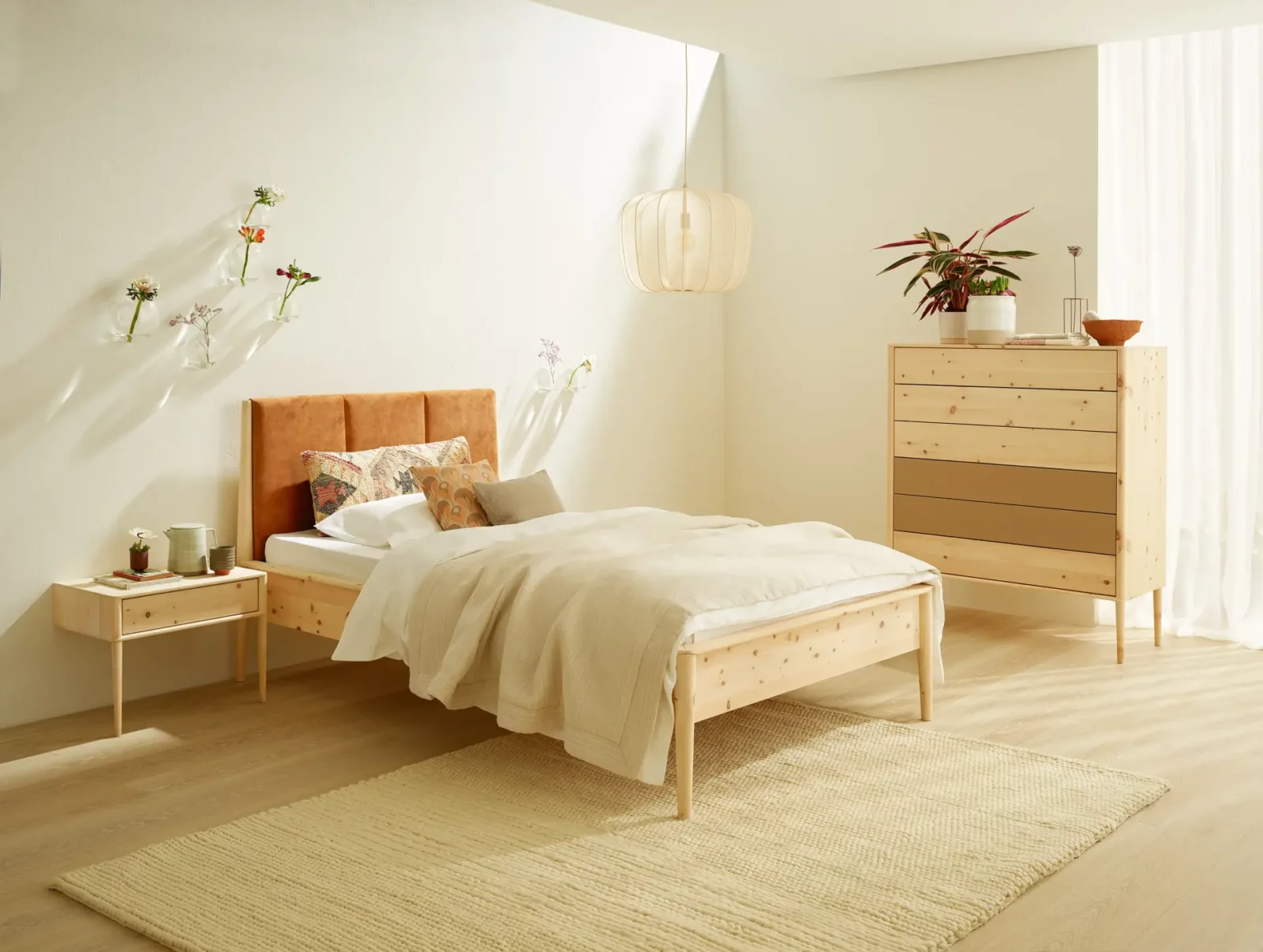 Anrei Juna Bett aus hellem Holz mit gepolstertem Kopfteil in Orange.