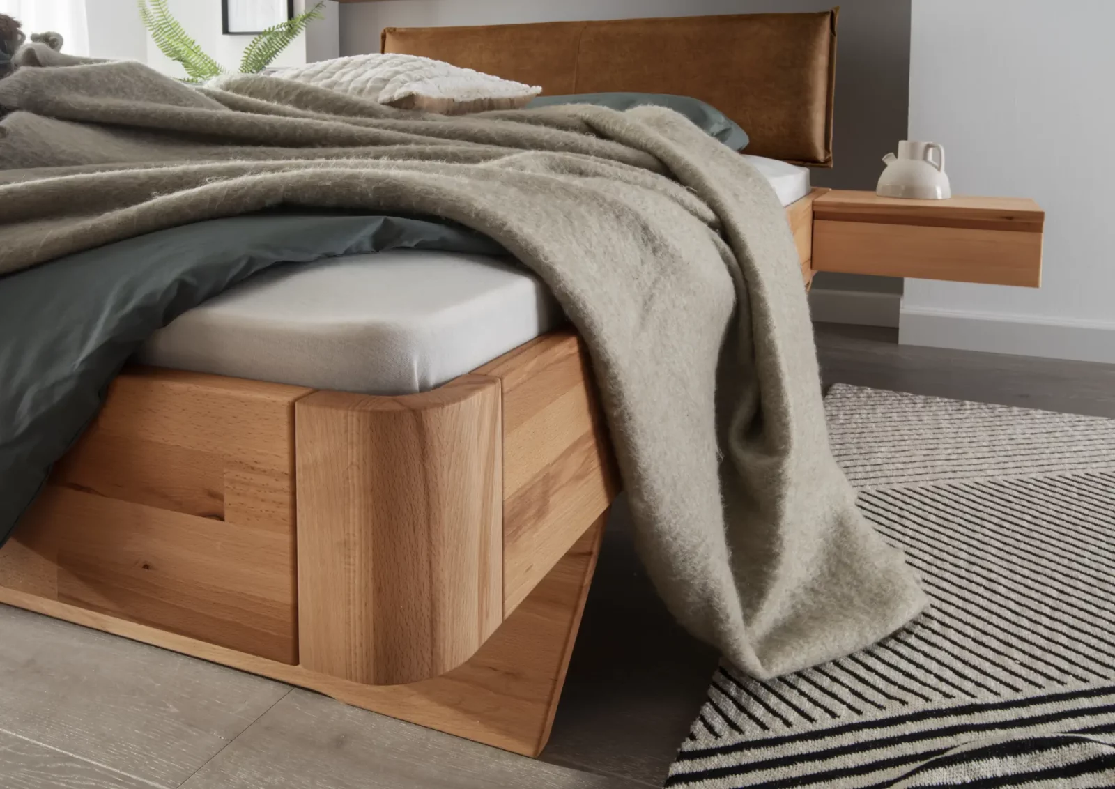 Bett Cleve aus hellem Holz mit gepolstertem Kopfteil und schwebendem Nachttisch.