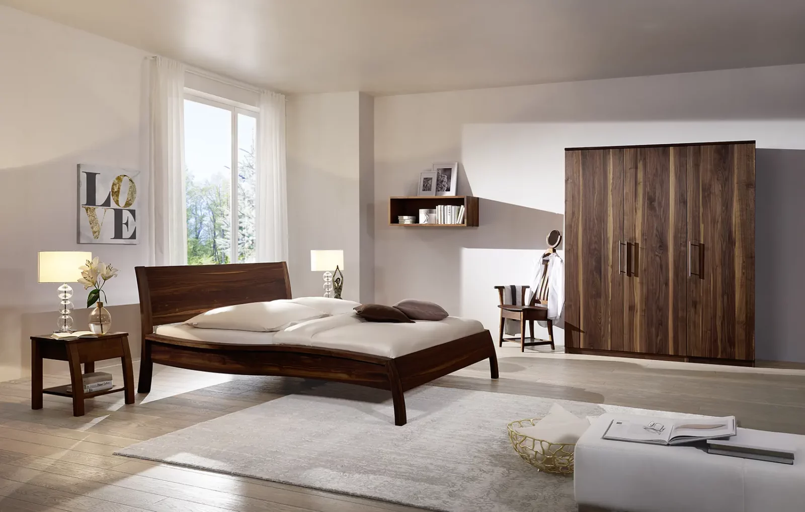 Holzschmiede Bett Kubus in dunklem Holz mit geschwungenem Kopfteil.