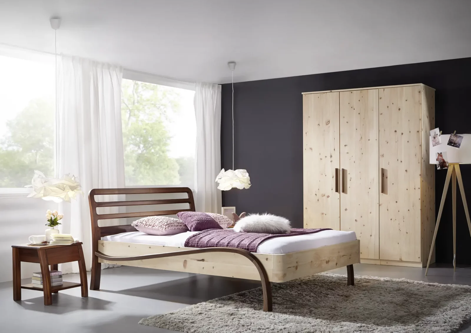 Holzschmiede Bett Kubus16 aus hellem Holz mit dunklem Kopfteil.
